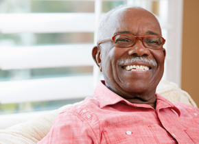 Older man smiling sitting on his sofa.